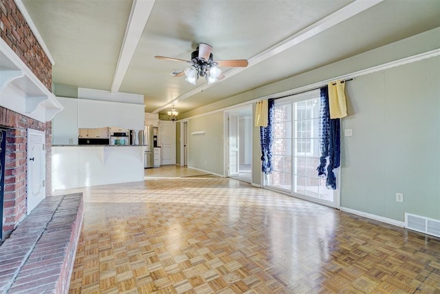 unfurnished living room featuring a brick fireplace, beam ceiling, light parquet flooring, and ceiling fan