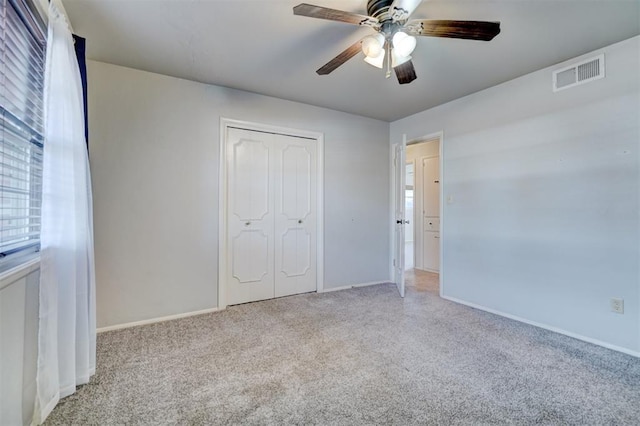 unfurnished bedroom with light carpet, ceiling fan, and a closet