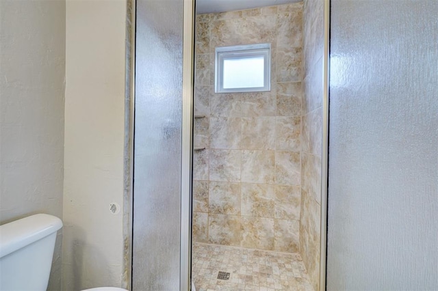 bathroom with a shower with shower door and toilet