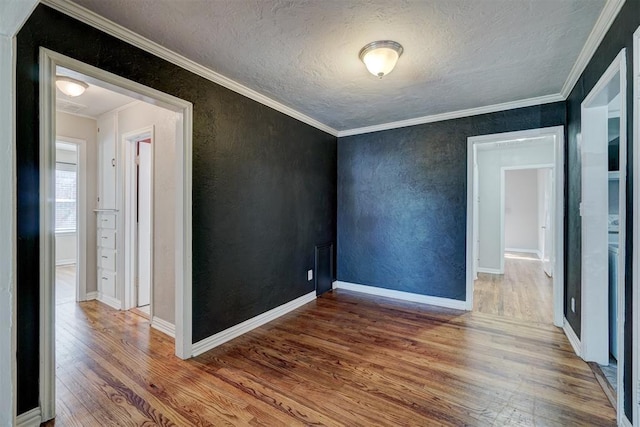 spare room featuring crown molding, hardwood / wood-style floors, and a textured ceiling