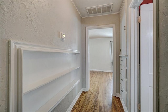 corridor with hardwood / wood-style floors and crown molding