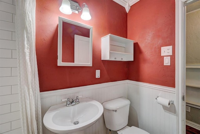 bathroom with ornamental molding, sink, and toilet