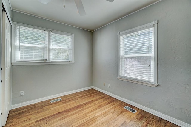 empty room featuring ceiling fan, a healthy amount of sunlight, and light hardwood / wood-style floors