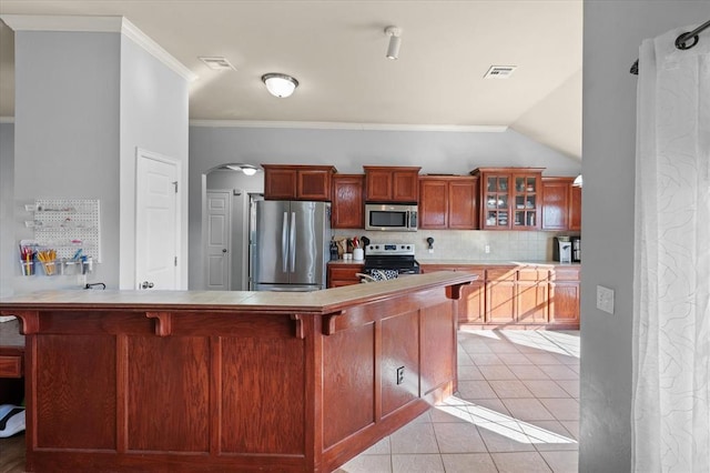 kitchen featuring a breakfast bar, light tile patterned floors, ornamental molding, appliances with stainless steel finishes, and backsplash