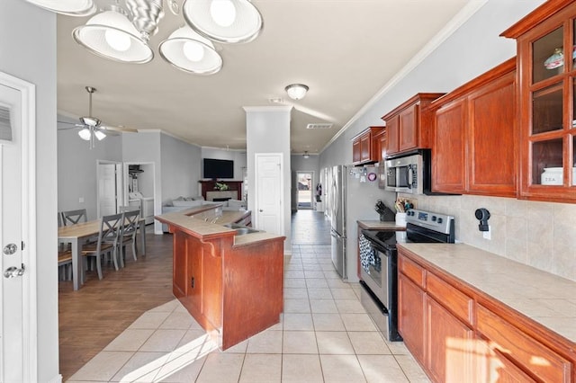 kitchen featuring light tile patterned flooring, tasteful backsplash, ornamental molding, appliances with stainless steel finishes, and ceiling fan