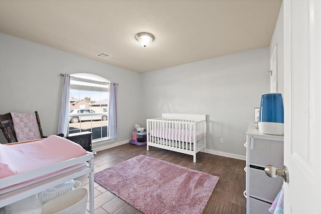 bedroom with dark wood-type flooring and a nursery area