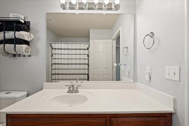 bathroom featuring walk in shower, vanity, and toilet