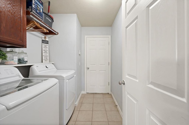 laundry room featuring light tile patterned floors, washer and clothes dryer, and cabinets