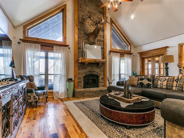 living room with a fireplace, hardwood / wood-style floors, high vaulted ceiling, and french doors