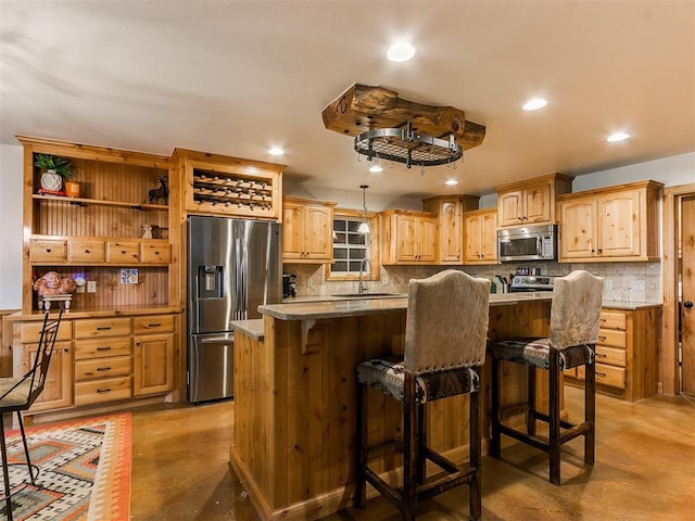 kitchen with a center island, appliances with stainless steel finishes, sink, concrete flooring, and a breakfast bar