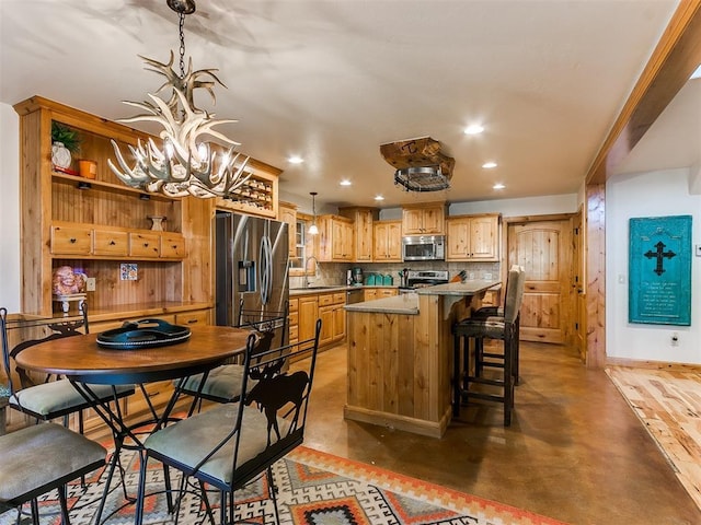 kitchen with sink, a kitchen island, a chandelier, a breakfast bar area, and stainless steel appliances