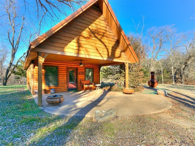 exterior space with a patio area, a lawn, a fire pit, and ceiling fan