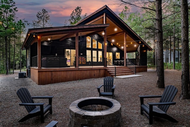 back house at dusk featuring central AC and an outdoor fire pit