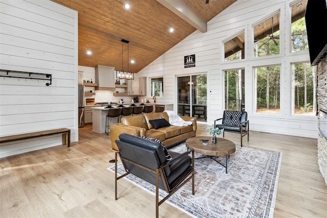 living room with plenty of natural light, high vaulted ceiling, light hardwood / wood-style floors, and beamed ceiling