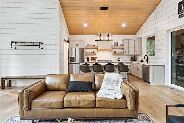 living room featuring lofted ceiling, sink, light wood-type flooring, and wooden ceiling