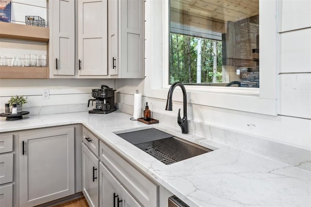 kitchen featuring light stone counters and sink