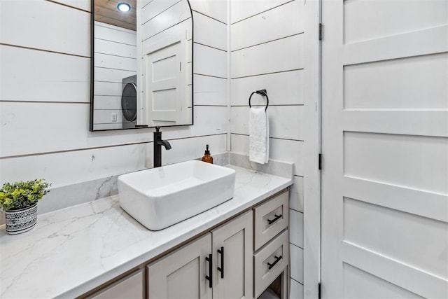 bathroom featuring vanity and wooden walls