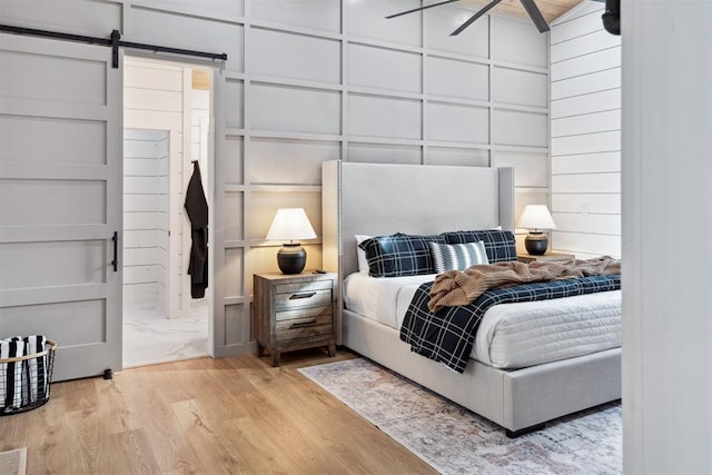 bedroom with light hardwood / wood-style flooring and a barn door