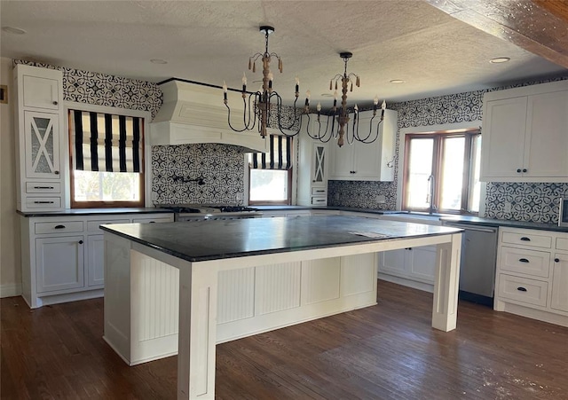 kitchen with white cabinetry, decorative light fixtures, a kitchen breakfast bar, dishwasher, and a kitchen island