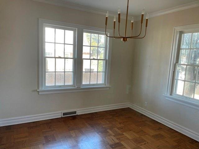 unfurnished dining area with an inviting chandelier, dark parquet flooring, ornamental molding, and a healthy amount of sunlight