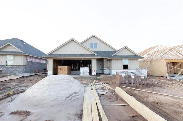 view of front facade with an attached garage, a shingled roof, and board and batten siding