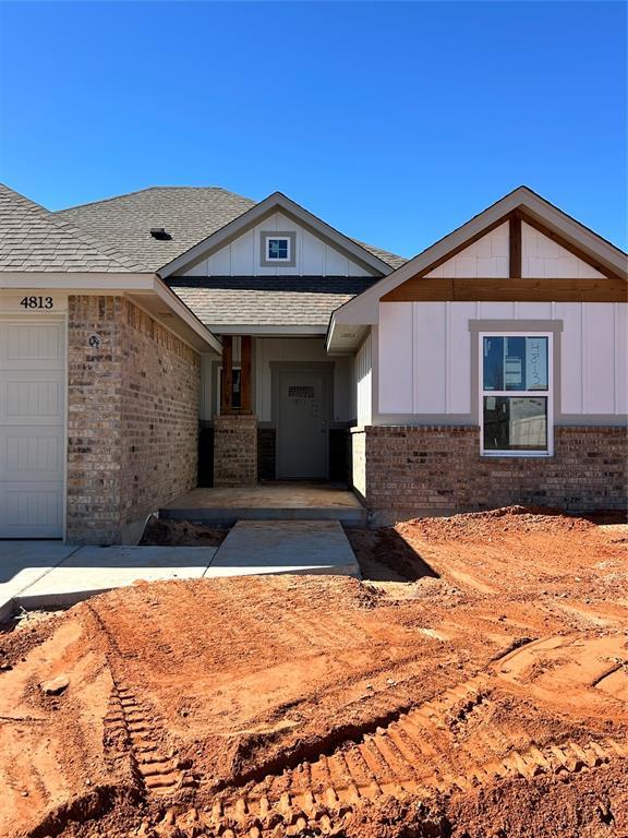 exterior space with a garage, brick siding, a shingled roof, and board and batten siding