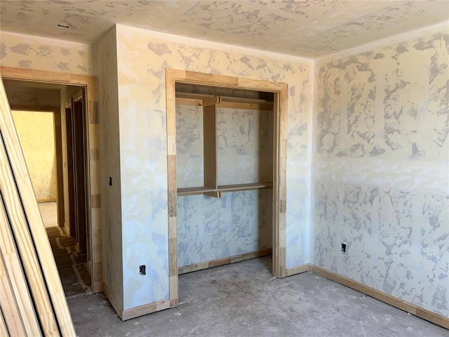 interior space with baseboards, concrete flooring, and wallpapered walls