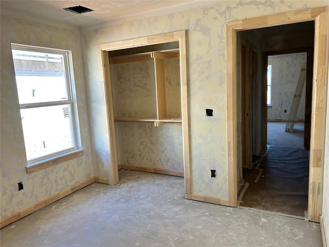 spare room featuring baseboards, unfinished concrete floors, and wallpapered walls