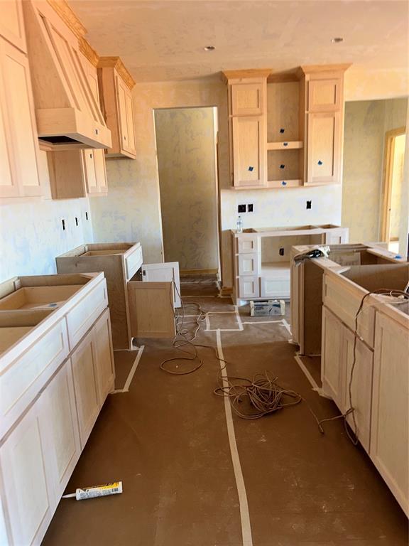 kitchen with concrete flooring, light brown cabinetry, and custom range hood