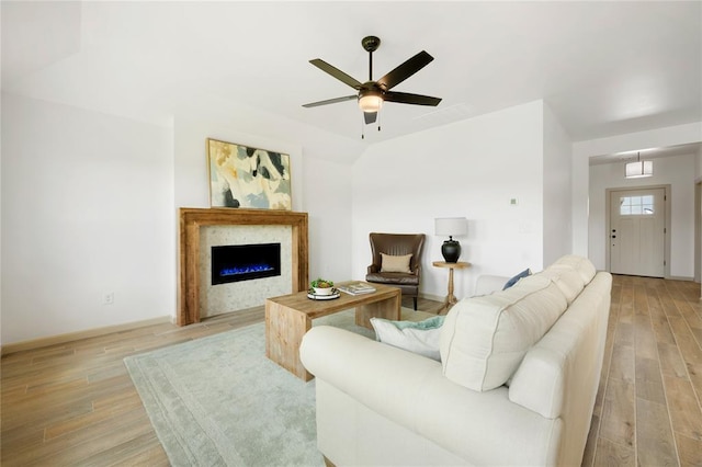 4813 Mistywood Ln, Mustang, OK 73064 - living room featuring light wood-style flooring, ceiling fan, a lit fireplace, and baseboards