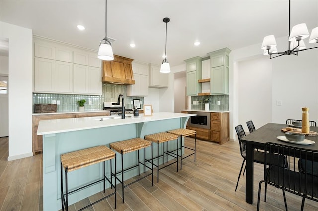 4813 Mistywood Ln, Mustang, OK 73064 - kitchen featuring custom range hood, light wood-style floors, tasteful backsplash, stainless steel microwave, and light countertops