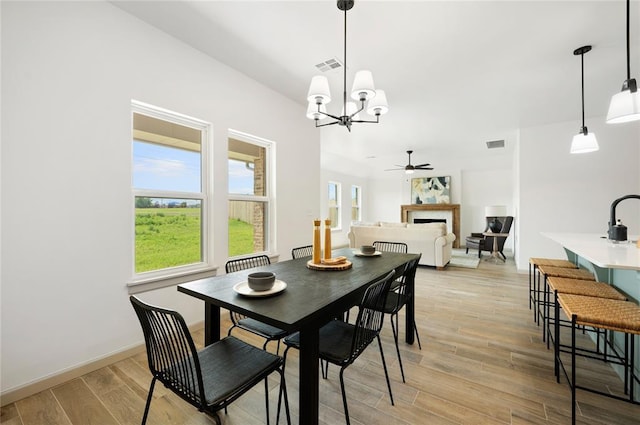 4813 Mistywood Ln, Mustang, OK 73064 - dining room with a ceiling fan, a chandelier, a fireplace, and light wood-style floors