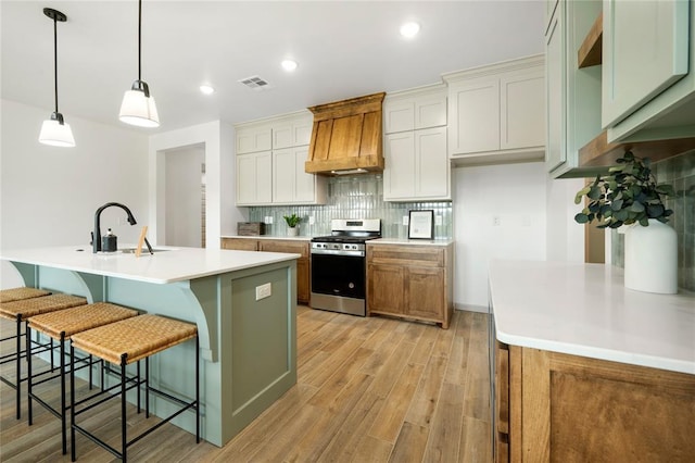 4813 Mistywood Ln, Mustang, OK 73064 - kitchen featuring stainless steel gas range oven, custom exhaust hood, a sink, light wood-style flooring, and backsplash
