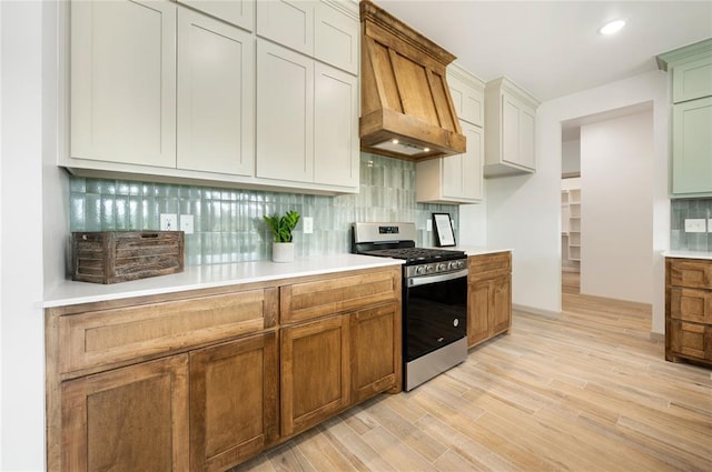 4813 Mistywood Ln, Mustang, OK 73064 - kitchen with stainless steel gas range oven, tasteful backsplash, light countertops, light wood-style floors, and custom range hood