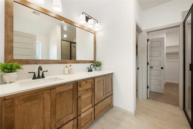 4813 Mistywood Ln, Mustang, OK 73064 - bathroom featuring double vanity, a stall shower, a walk in closet, tile patterned floors, and baseboards