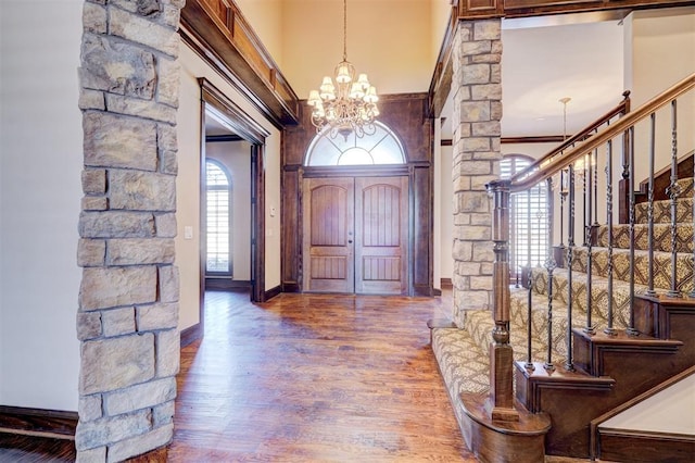 entryway with hardwood / wood-style floors, crown molding, and a notable chandelier