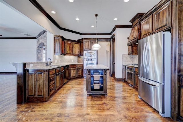 kitchen featuring pendant lighting, sink, a kitchen island, decorative backsplash, and stainless steel appliances