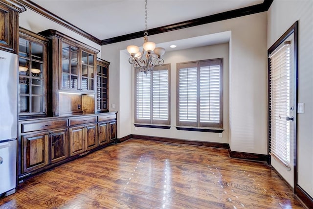 dining space with crown molding, dark hardwood / wood-style floors, and an inviting chandelier