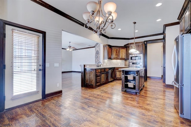 kitchen featuring a kitchen island, decorative light fixtures, stainless steel appliances, decorative backsplash, and ornamental molding