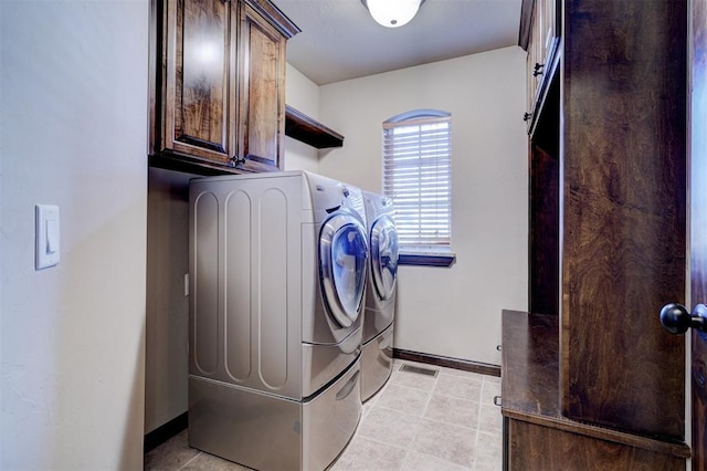 clothes washing area featuring washing machine and dryer, light tile patterned floors, and cabinets