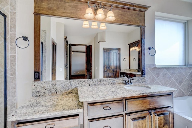 bathroom with vanity, backsplash, a wealth of natural light, and a tub