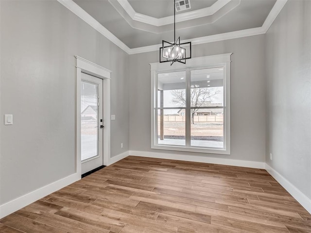 unfurnished dining area with light hardwood / wood-style flooring, a chandelier, crown molding, and a tray ceiling