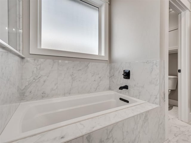 bathroom with toilet and tiled bath