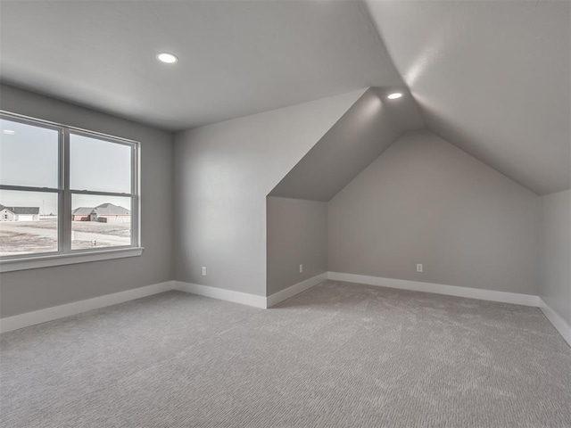 bonus room featuring vaulted ceiling and light carpet