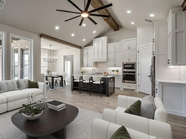 living room featuring sink, high vaulted ceiling, beamed ceiling, and light wood-type flooring