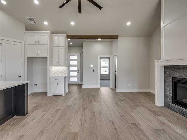 kitchen with tasteful backsplash, a fireplace, light hardwood / wood-style floors, and white cabinets