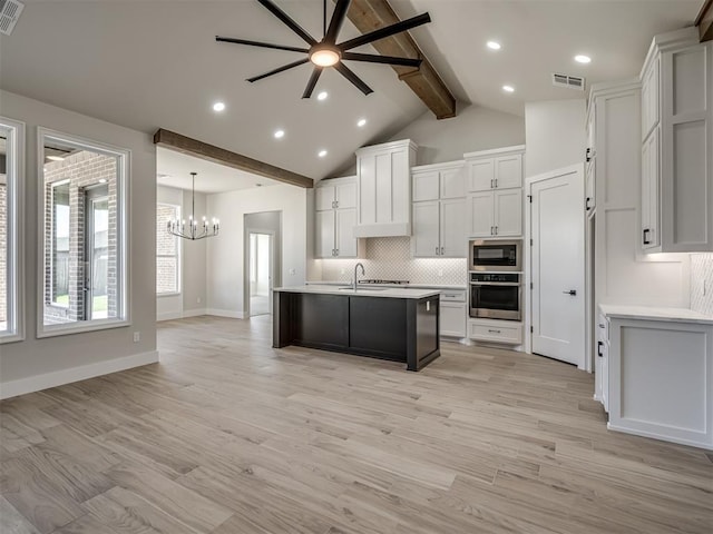 kitchen featuring white cabinetry, oven, a center island with sink, and built in microwave