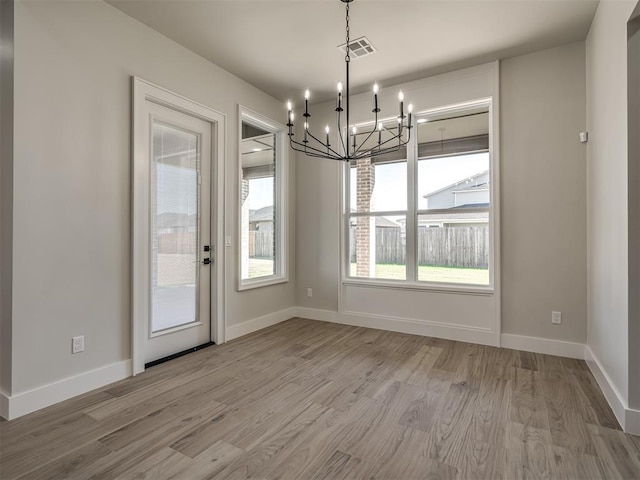 unfurnished dining area featuring an inviting chandelier and light wood-type flooring