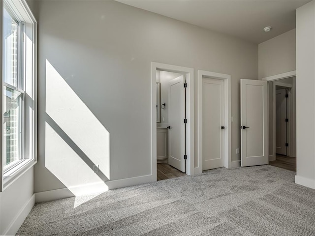 interior space with light colored carpet, connected bathroom, and multiple windows