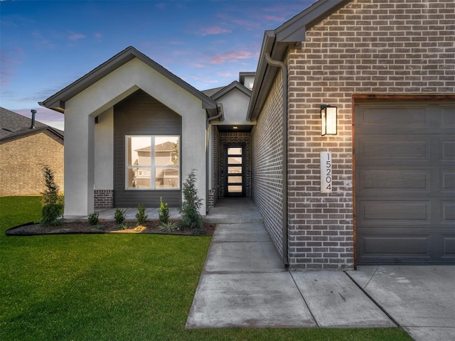 exterior entry at dusk with a garage and a lawn